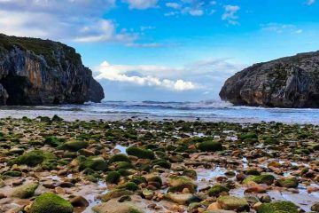 Paisaje de rocas y acantilados en la Playa de las Cuevas del Mar durante la ruta en furgoneta camper por Asturias de Juanma y Elena de Van and to Discover