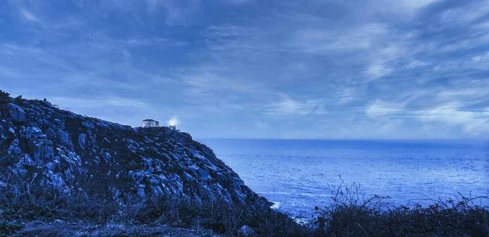 Faro de Finisterre encendido sobre el acantilado del océano Atlántico durante el viaje a Galicia en furgoneta camper de Van and to Discover