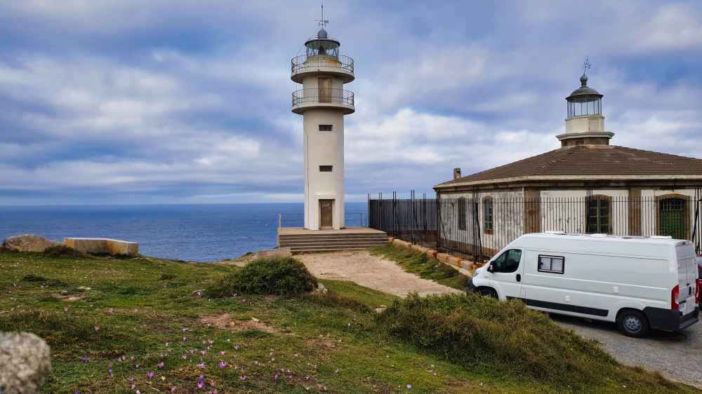 Furgoneta camper aparcada junto al Faro de Touriñan y la antigua casa fareros