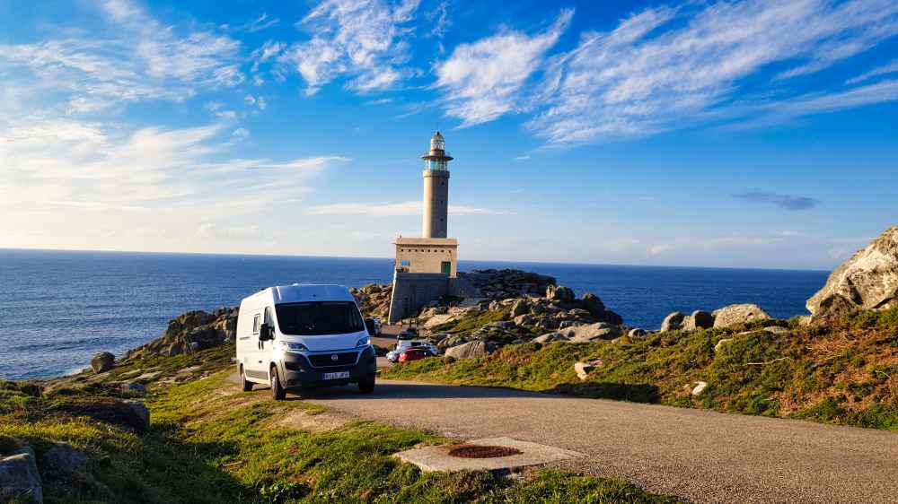 Furgoneta camper circulando por la carretera de acceso al Faro de Punta Nariga en la Costa da Morte, Galicia.