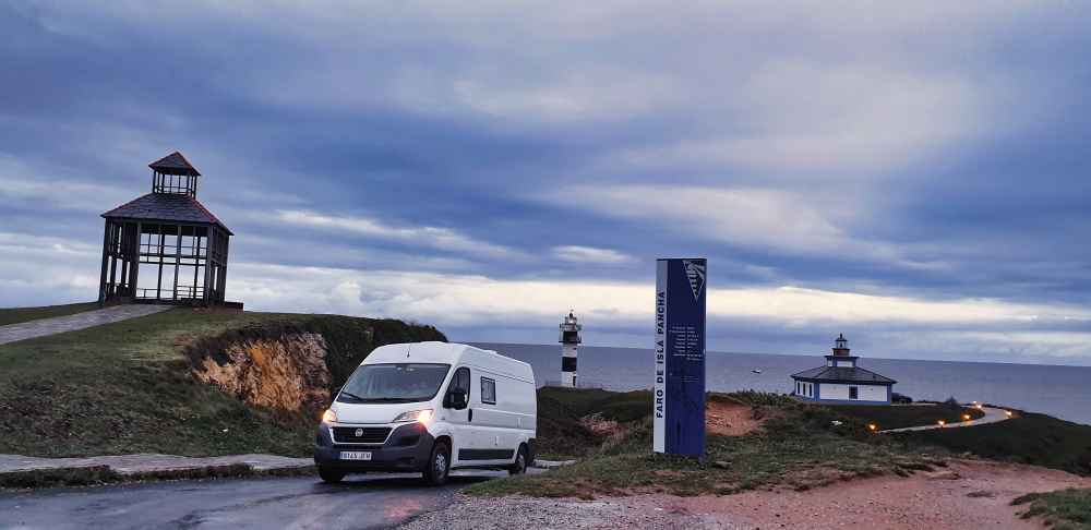 Furgoneta camper de Van and to Discover en Isla Pancha de Ribadeo con sus faros al fondo durante su viaje por Galicia