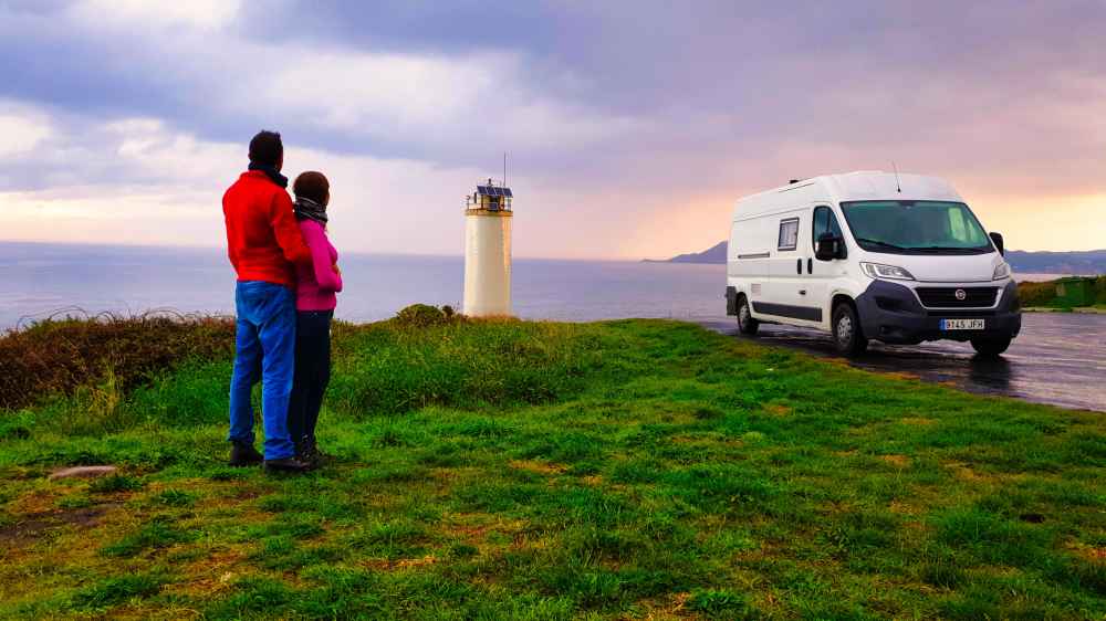 Juanma y Elena de Van and to Discover observando el atardecer junto a su furgoneta camper frente al mar de la Costa da Morte