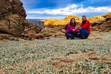 Juanma y Elena de Van and to Discover sentados en la Playa de los Cristales de Laxe en la ruta de Galicia en furgoneta camper
