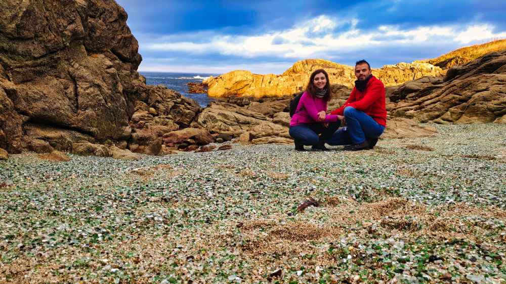 Juanma y Elena de Van and to Discover sentados en la Playa de los Cristales de Laxe en la ruta de Galicia en furgoneta camper