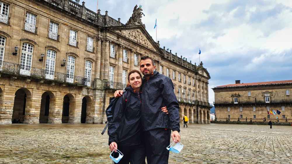 Juanma y Elena de (Van and to Discover) con chubasqueros en la Plaza del Obradoiro de Santiago de Compostela bajo la lluvia