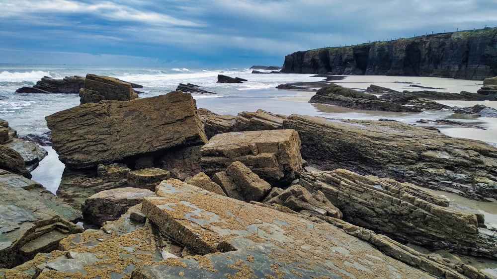 Desprendimientos de piedra sobre la arena tras el derrumbe de un arco en la Playa de las Catedrales en Galicia