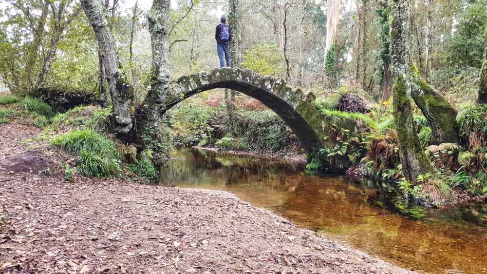 Juanma de Van and to Discover sobre el antiguo puente medieval de piedra de Xuño cruzando el río Sieira