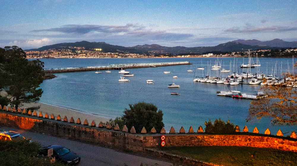 Vista del puerto y de la bahía de Bayona con los barcos amarrados al anochecer