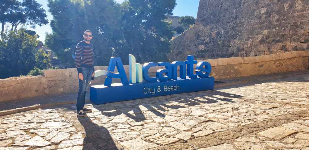 Juanma de Van and to Discover junto al letrero turรญstico de Alicante a las puertas del Castillo de Santa Barbara en el viaje a Alicante en furgoneta camper