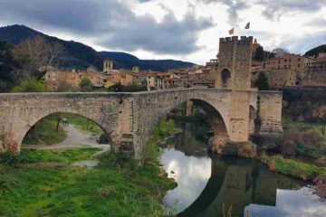 Vista del puente medieval fortificado de Besalú reflejado sobre el río en una ruta por Cataluña