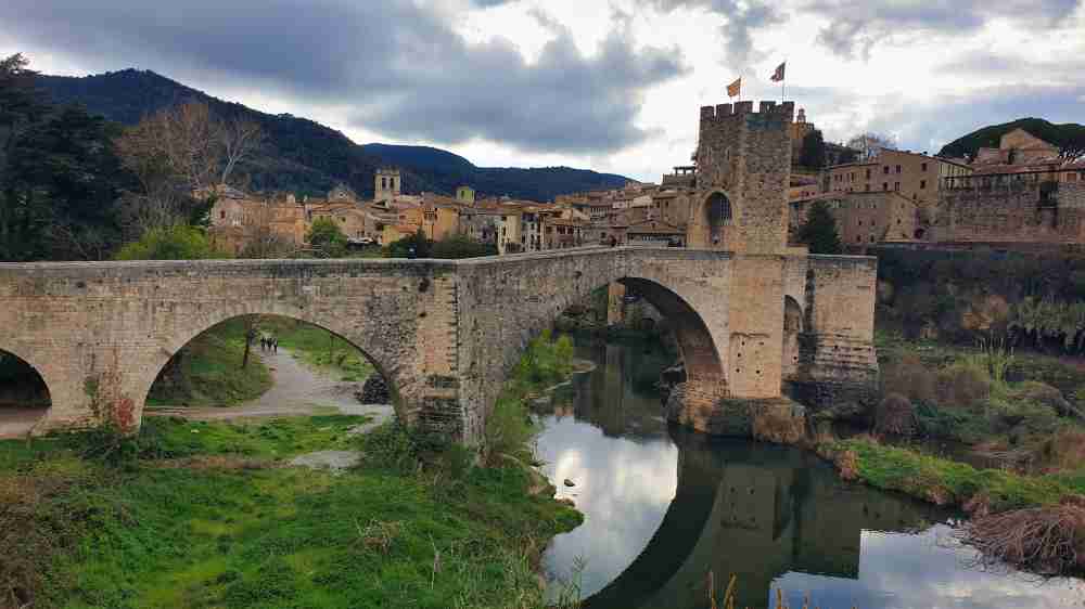Vista del puente medieval fortificado de Besalú reflejado sobre el río en una ruta por Cataluña