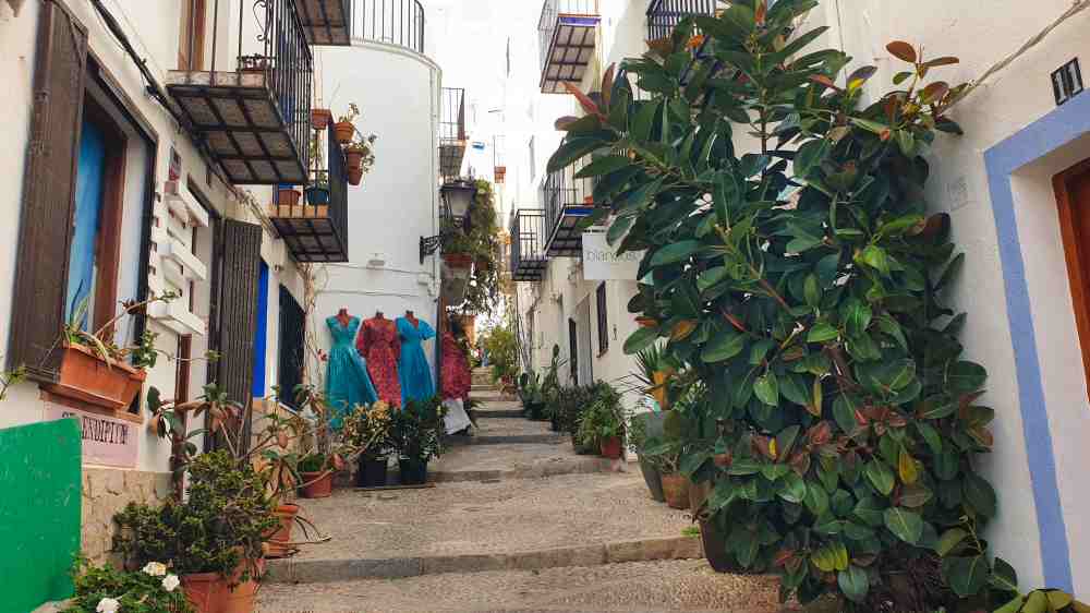 Calle empedrada típica del casco antiguo de Peñíscola con fachadas blancas y puestos de artesanía local