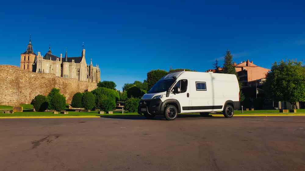Furgoneta camper de Van and to Discover estacionada en Astorga con el Palacio Episcopal de Gaudí al fondo